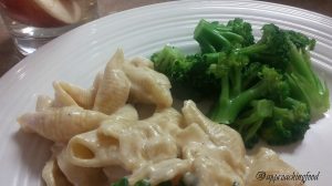 Plated pasta with broccoli and glass of iced tea.